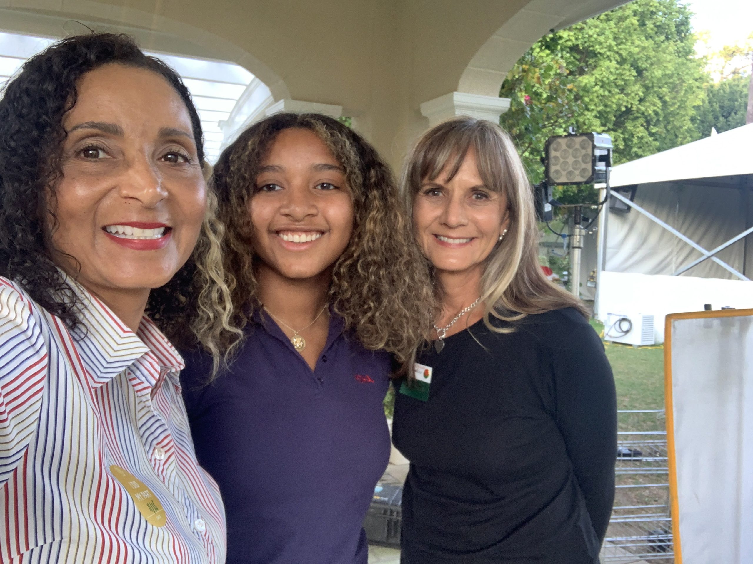 Patricia Nazario and Cricket Wheeler pose with 2022 Rose Princess McKenzie Street during a KTLA Rose Parade field production at Tournament House.
